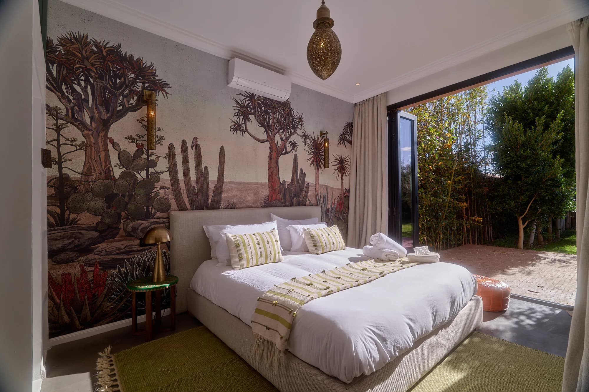 Suite indépendante de Villa Yemna avec fresque végétale, lit king size, tons naturels et baie vitrée donnant sur le jardin.
