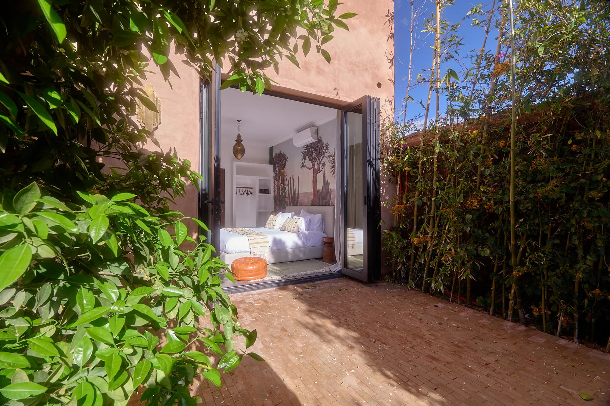 Terrasse privée d’une suite de Villa Yemna, encadrée par la végétation, avec baie vitrée ouverte sur une chambre lumineuse.