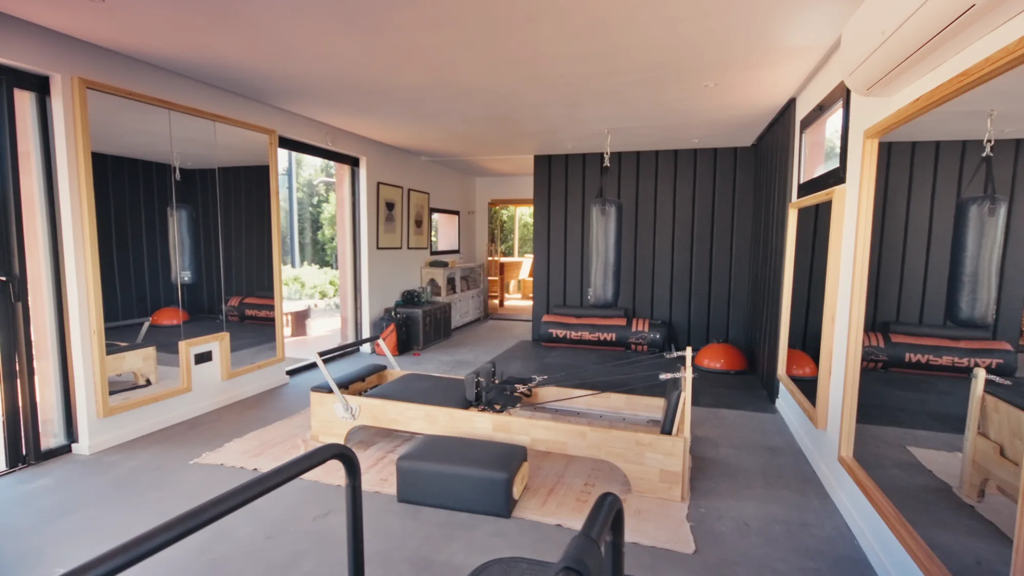 Salle de sport privée de Villa Yemna à Marrakech avec machine de Pilates Reformer, sacs de frappe, demi-sphères Bosu et miroirs muraux.