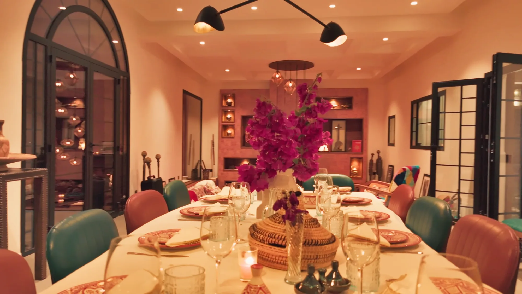 Table à manger dressée du riad de Villa Yemna à Marrakech avec bougainvilliers fuchsia en centre de table, verres en cristal et vaisselle marocaine.