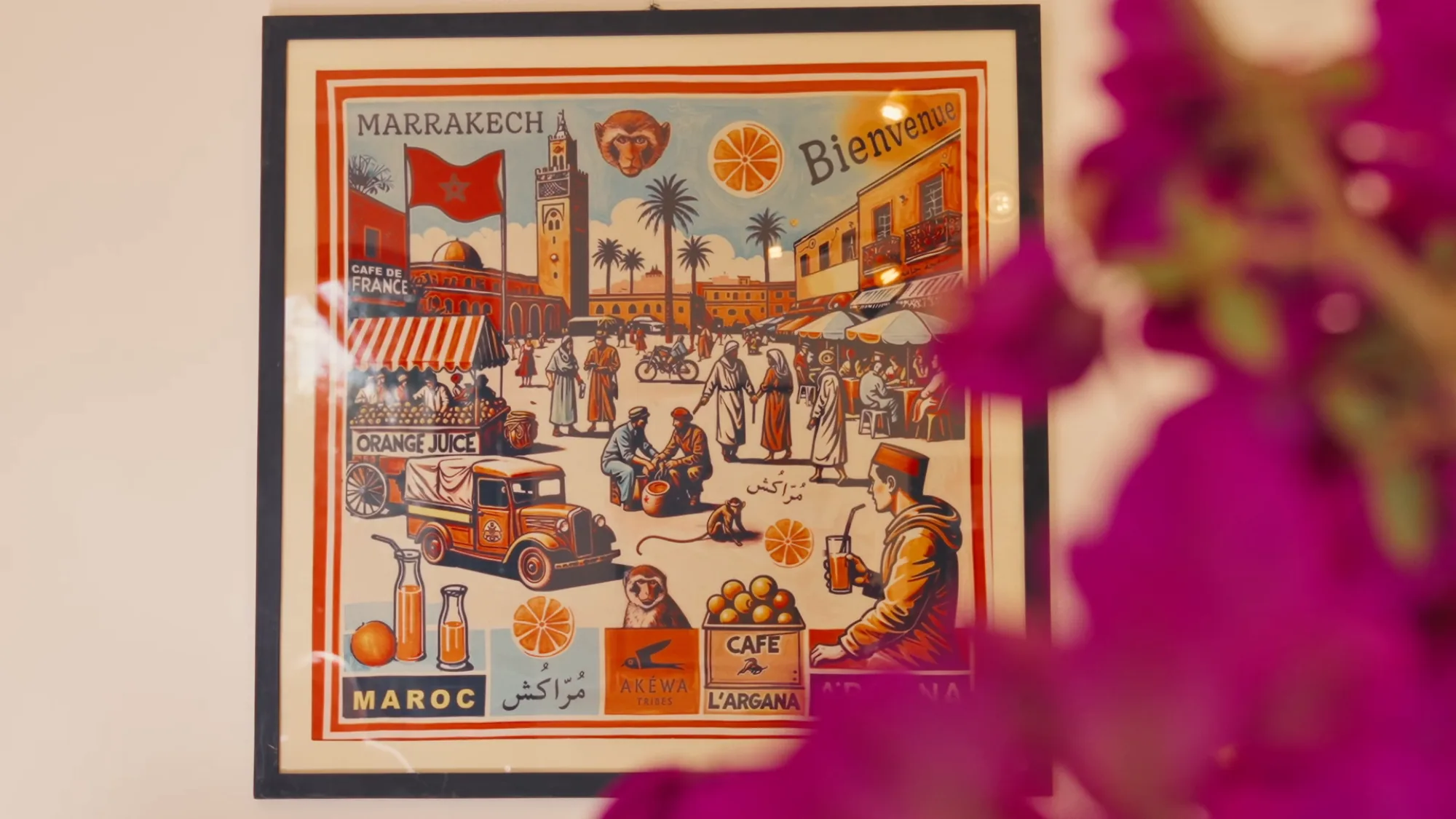 Décor de la cuisine du riad de Villa Yemna avec affiche vintage Bienvenue à Marrakech encadrée et bougainvillier rose au premier plan.