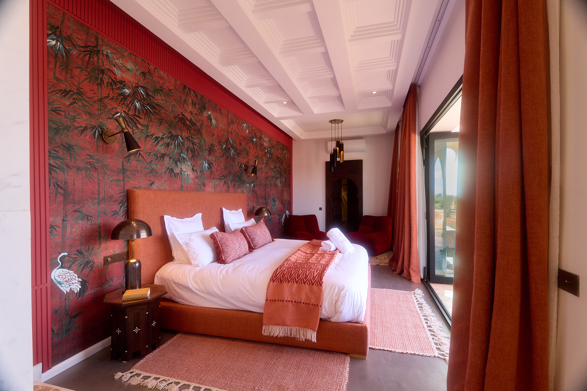 Vue latérale de la Suite Oukaimeden à Villa Yemna, avec lit king size, rideaux terracotta et baie vitrée vers la terrasse.