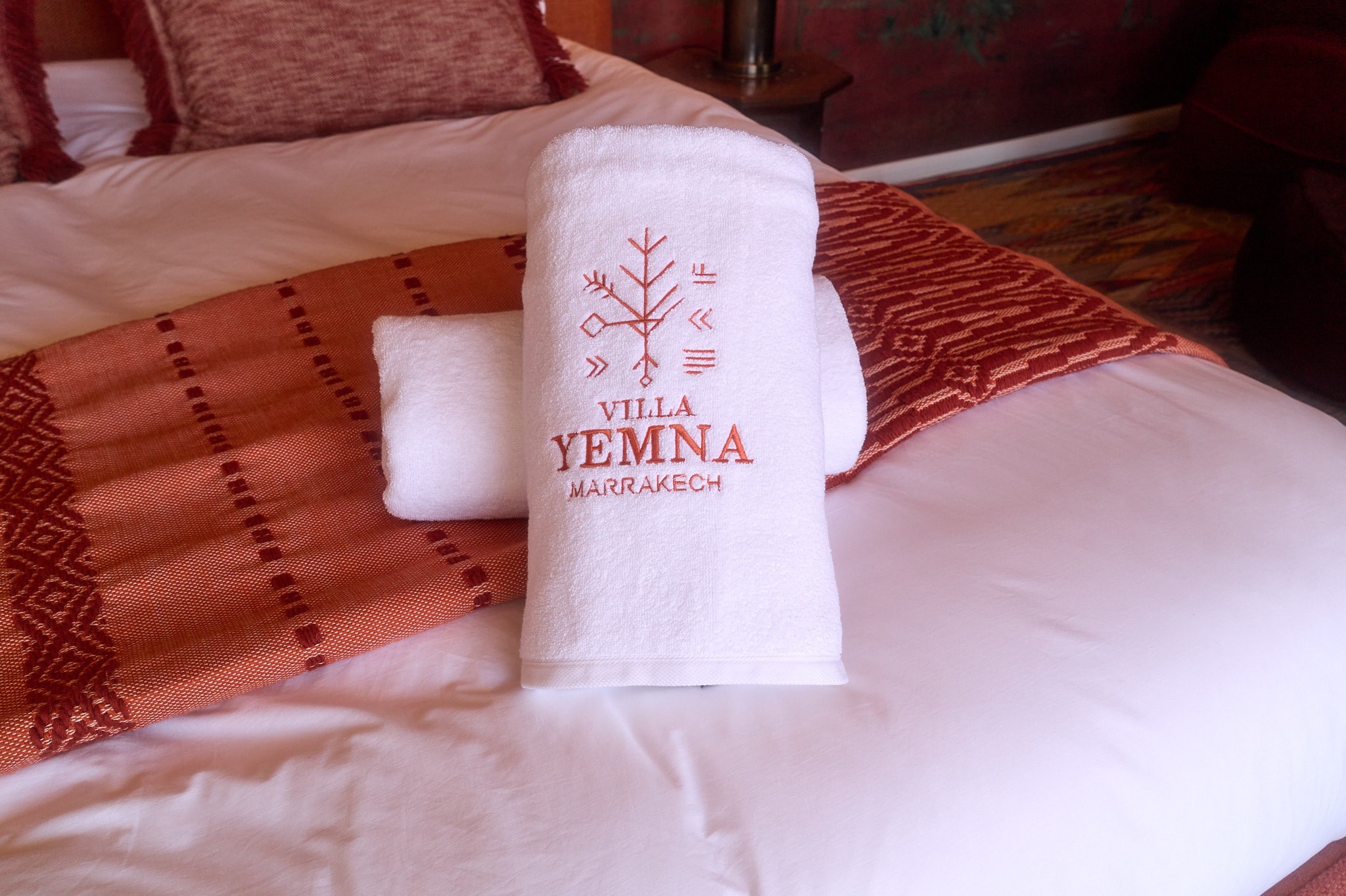 Détail de serviettes brodées Villa Yemna posées sur le lit de la Suite Oukaimeden.