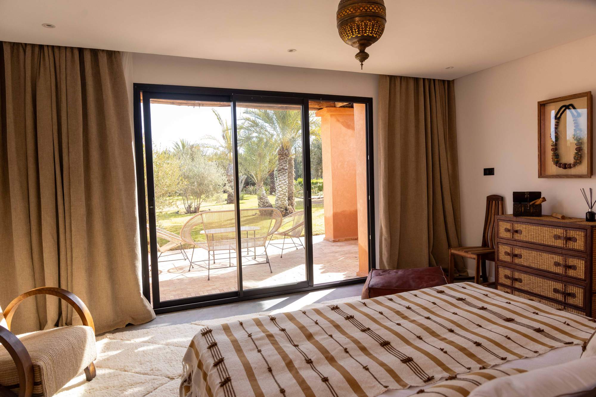 Suite Imi Ouaddar de la Villa Yemna à Marrakech, chambre ouverte sur la terrasse aux palmiers, vue intérieure.