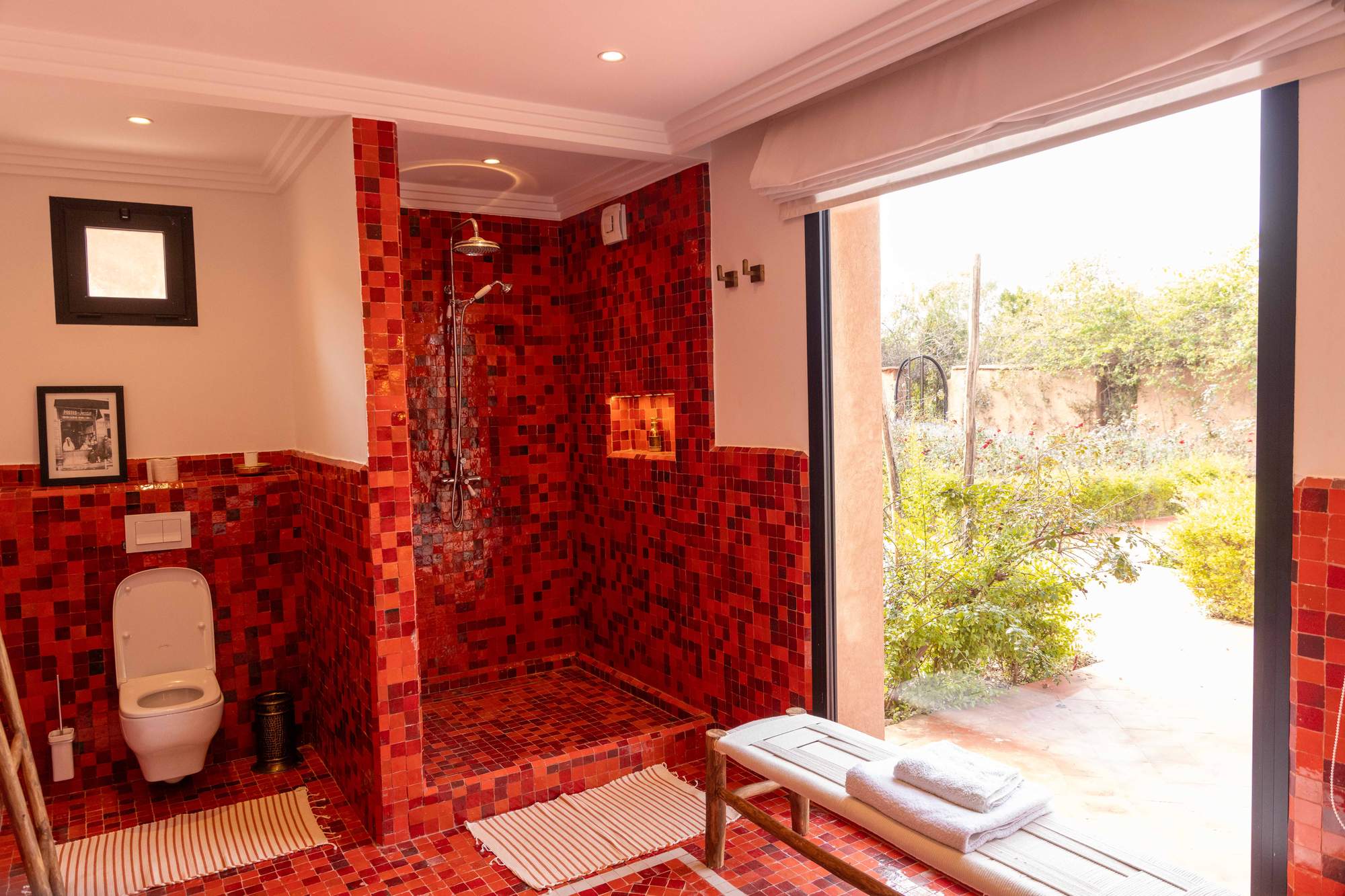 Suite Imlil de la Villa Yemna à Marrakech, salle de bain avec douche rouge, vue sur le jardin.
