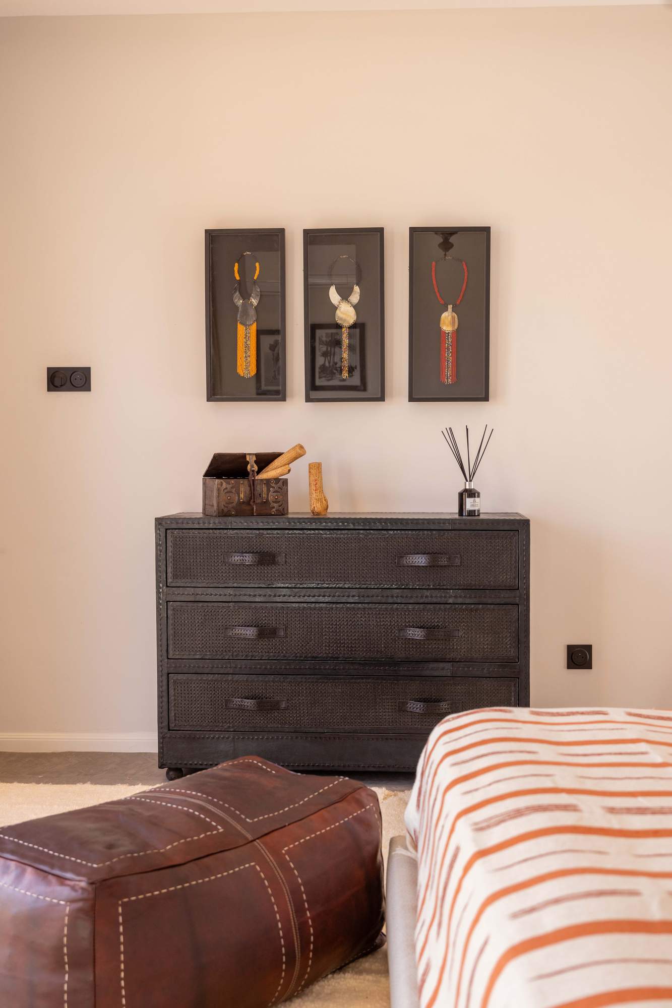 Suite Ourika de la Villa Yemna à Marrakech, chambre avec commode et pouf en cuir.