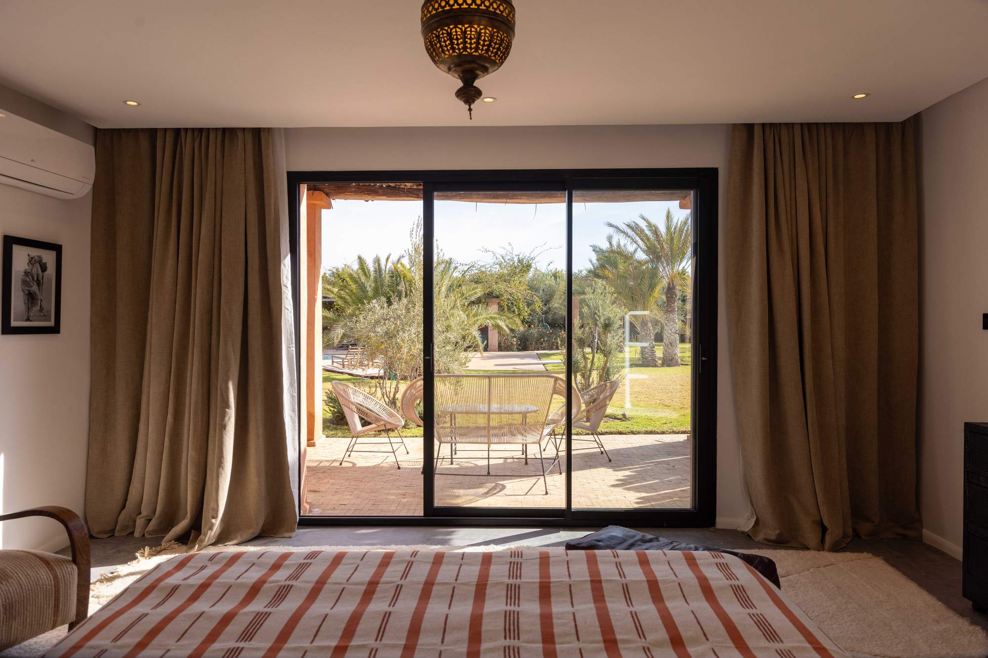 Suite Ourika de la Villa Yemna à Marrakech, chambre avec vue sur la terrasse aux palmiers.