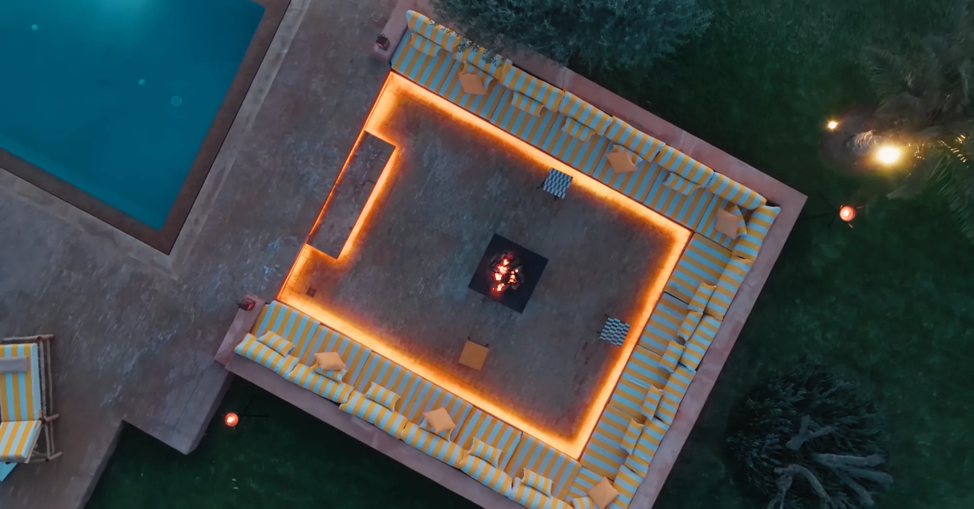Vue drone nocturne de la piscine et du salon brasero illuminé à Villa Yemna.