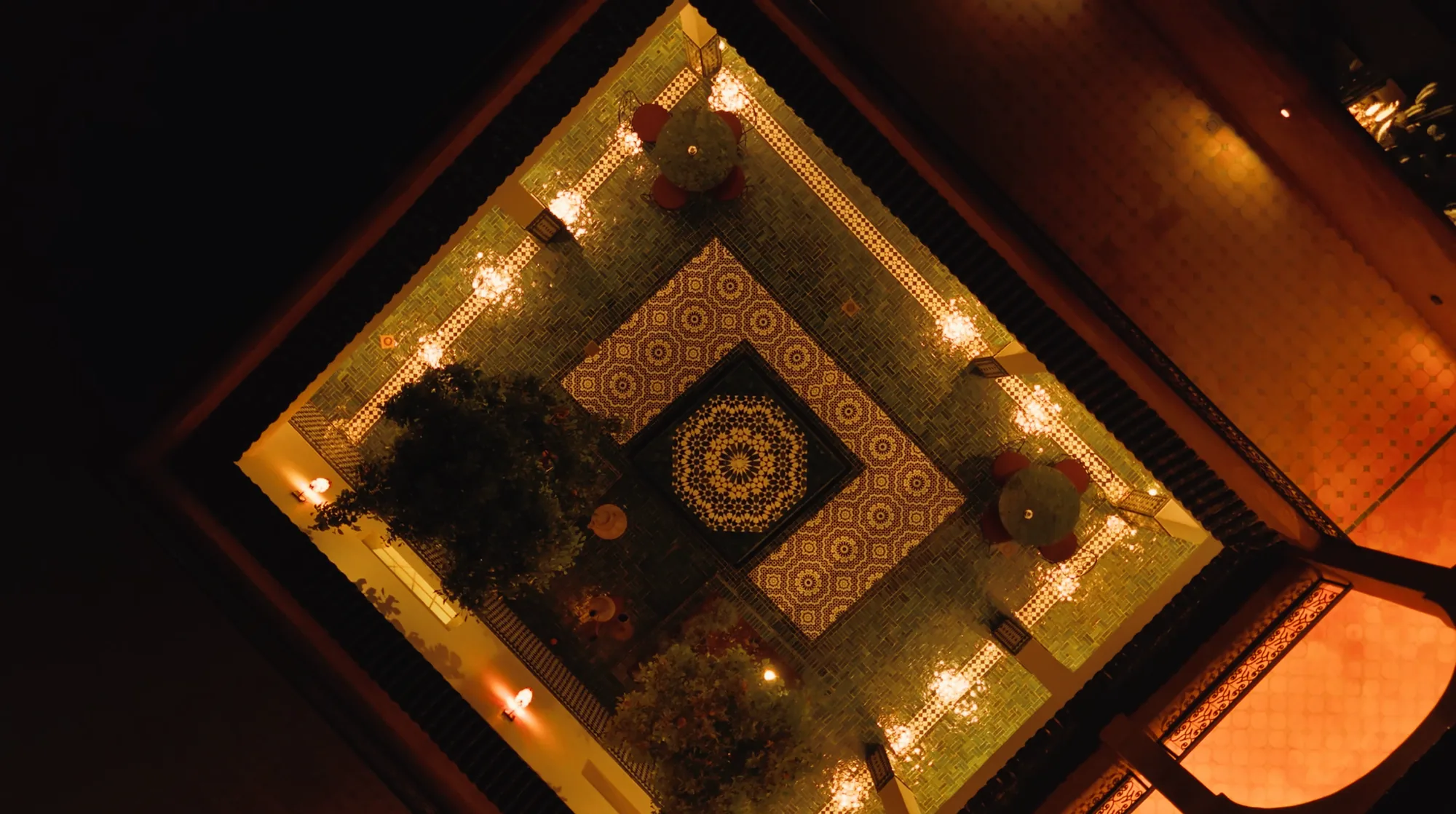 Vue drone de nuit de la cour du riad illuminée avec fontaine centrale à Villa Yemna.